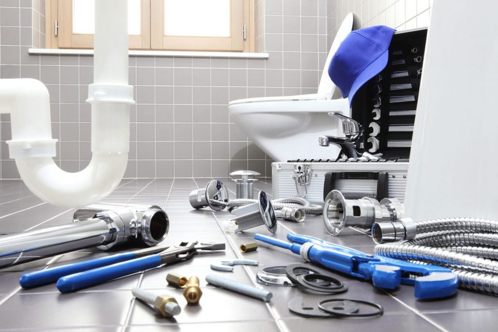 Find the right plumbing tools for the job. Various tools are laid out before pipe and toilet.