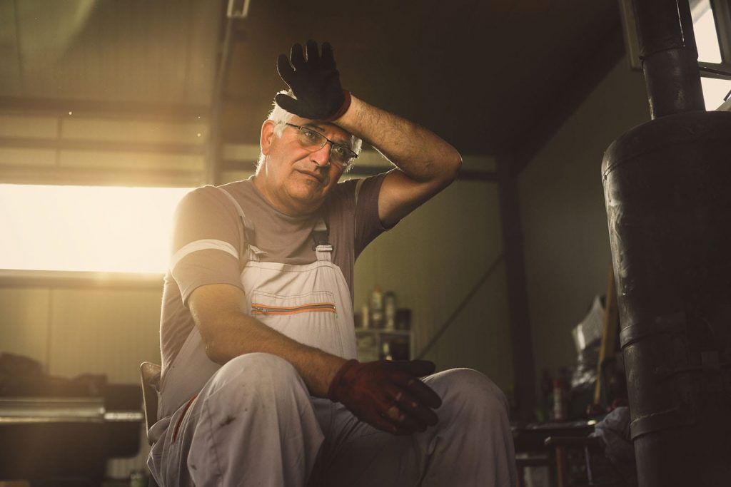 An older man fixes a furnace and sweats. Furnace noises are common, but it's when you hear them that's significant.