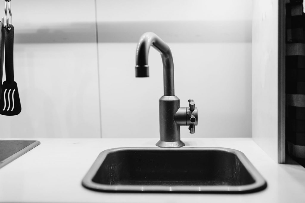 A black sink and faucet. Diagnosing plumbing issues can be as easy as identifying garbage disposal sounds.