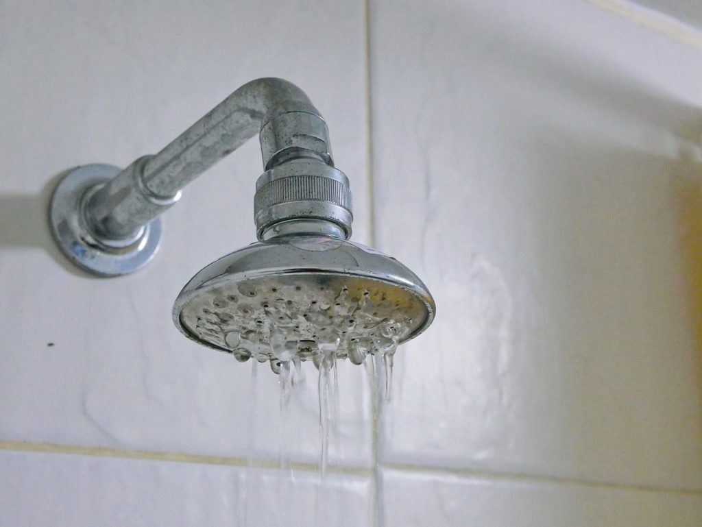 Low water pressure can be a simple fix, or escalate to calling the local water department. A showerhead dripping water.