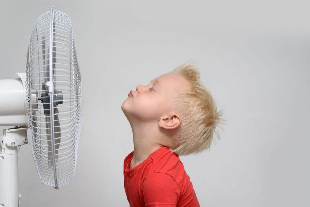 Heating and cooling costs differ from state to state. A kid sits in front of a fan trying to cool down.